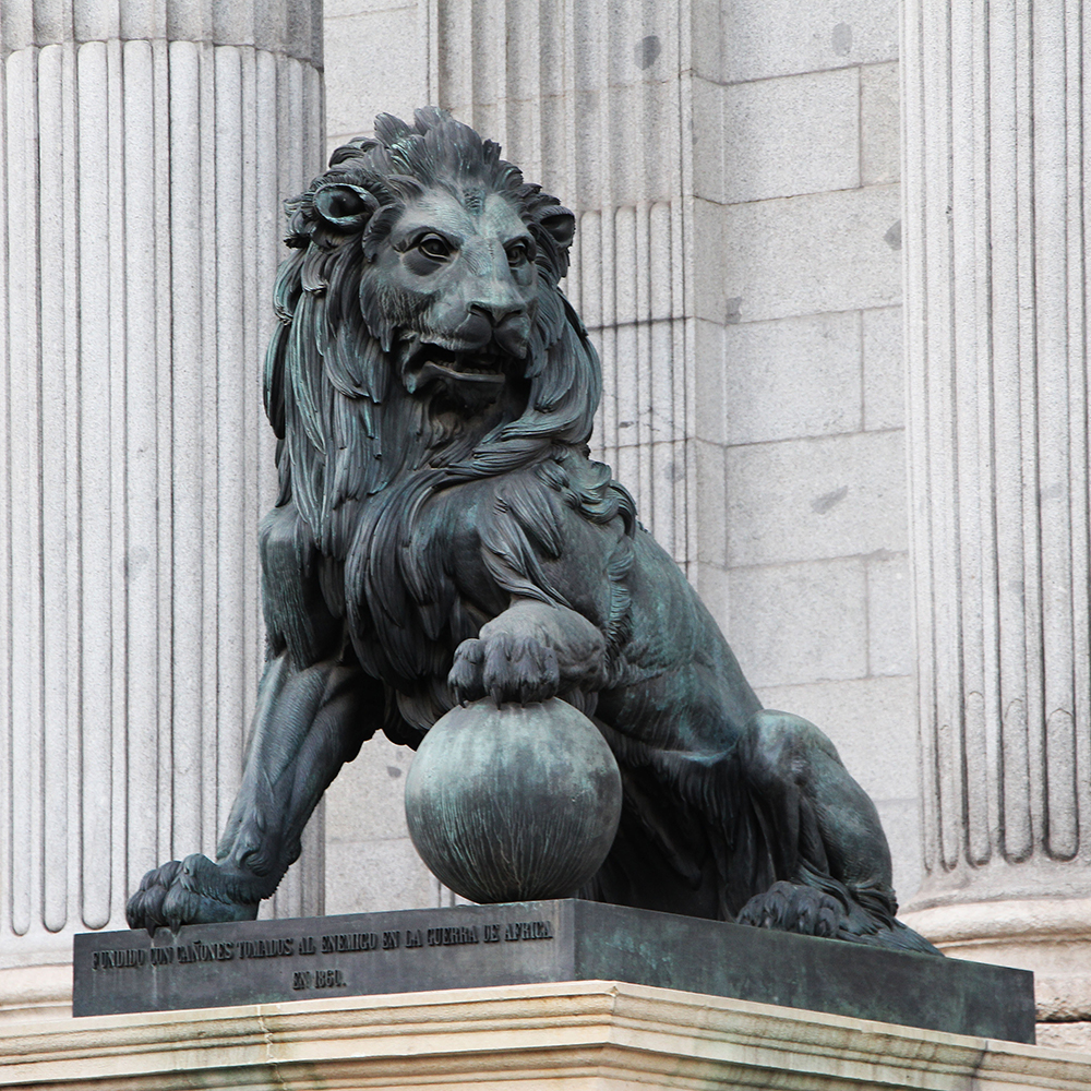 Escultura de león en la entrada de un edificio con columnas estriadas