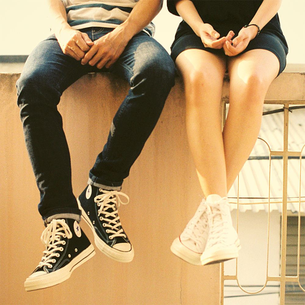 Piernas de dos personas sentadas con zapatillas deportivas